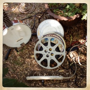 Photo of a banjo, film reels and a power strip on the ground at a Dumfuxx photo shoot.