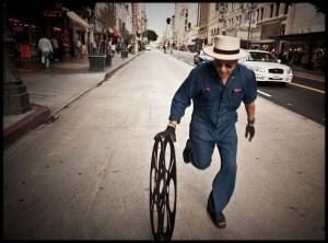Photo of Carlos Grasso of Dumfuxx rolling a film reel on a street.