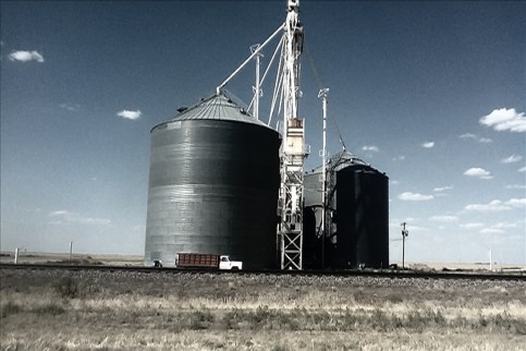 Photo of a grainery off of a highway.